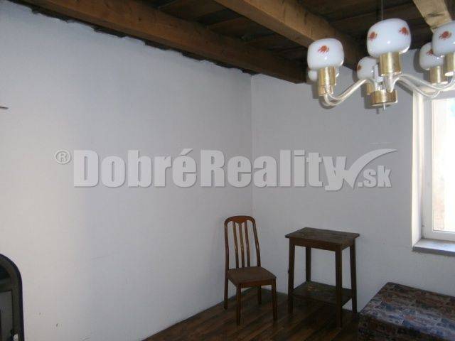A simply furnished room in a family house with a wooden ceiling and floor.