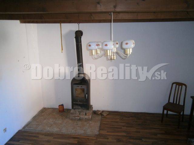 Interior of a family house with a stove, wooden chair, and wall lamp.