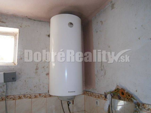 An electric boiler in a family house with wall cladding and a small window.