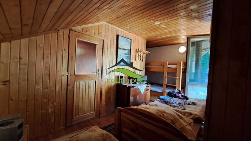 A room in a cabin with wooden paneling, a bunk bed, and furniture.