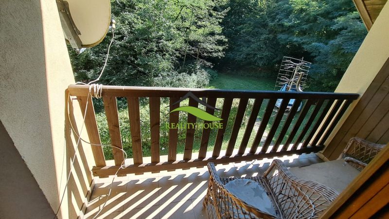 View from the cabin in Kvakovce at Dobrá, wooden railing, greenery, terrace chairs.