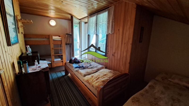 The interior of a cabin with a bunk bed, simple furniture, and a wooden ceiling.