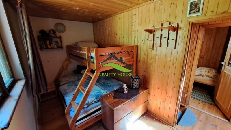 Bunk bed in a cozy room with wooden paneling in a cabin.