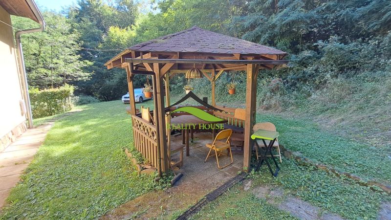 A wooden gazebo next to the cottage in Dobrá in Kvakovce with garden seating surrounded by greenery.