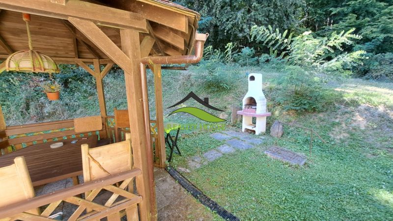 A wooden gazebo with a grill at the cottage in Dobrá, Kvakovce, surrounded by greenery and trees.