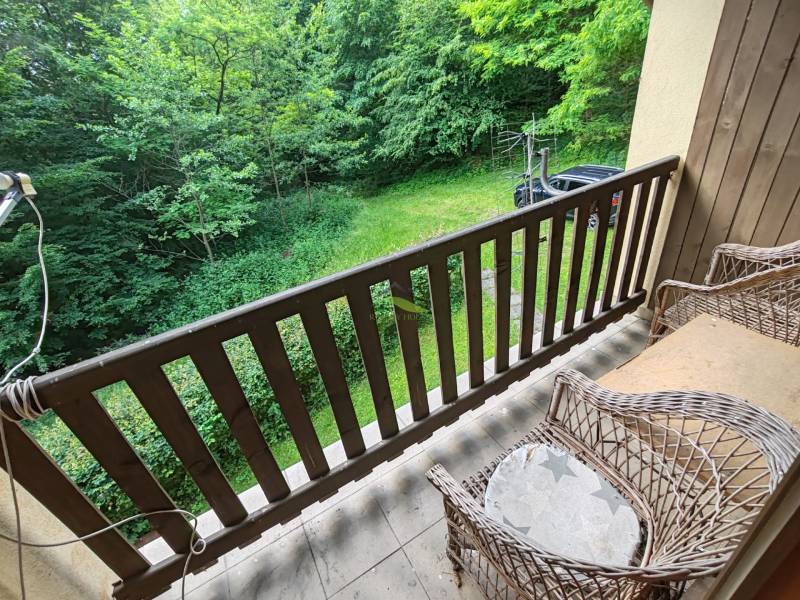 The balcony of the cottage with wicker chairs and a view of the garden and greenery.