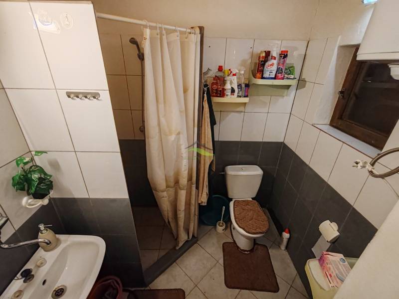 A bathroom in a cabin with a toilet, shower, and white tiles.