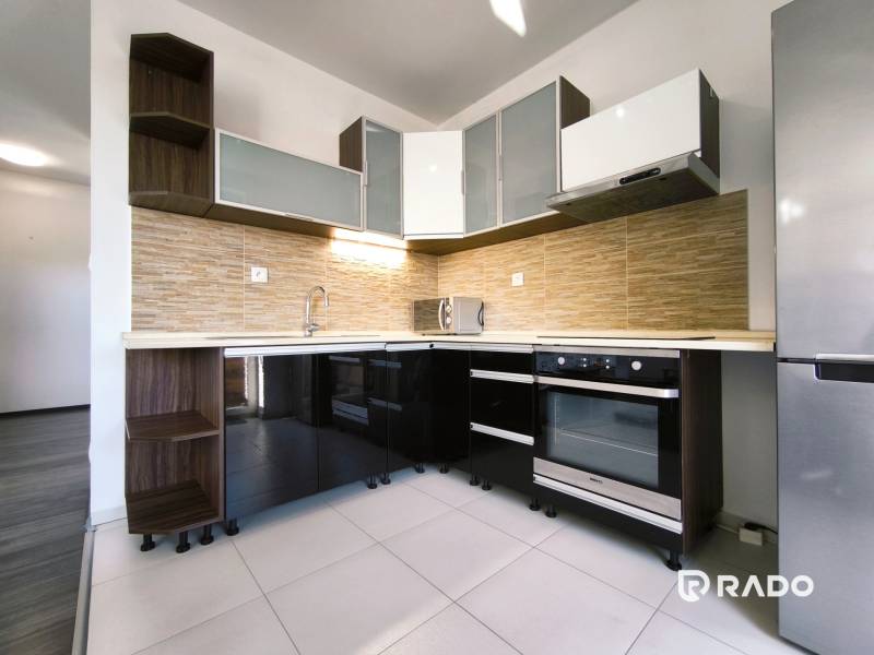 A kitchen in a 2-room apartment with a modern unit, appliances, and storage space.