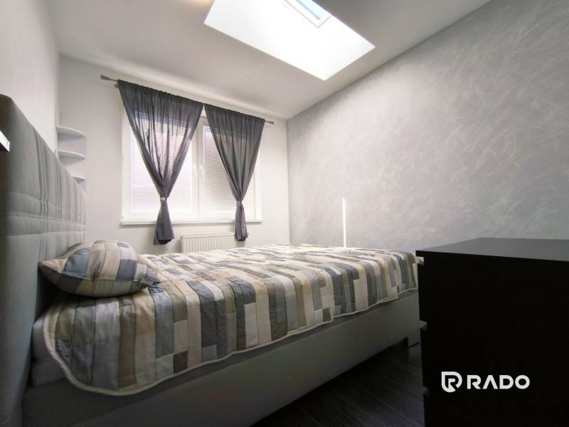 A bright bedroom with a double bed and a dresser in a 2-room apartment.