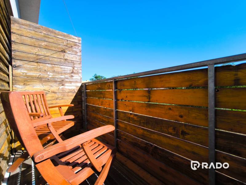 A balcony with wooden chairs and a railing in a 2-room apartment.