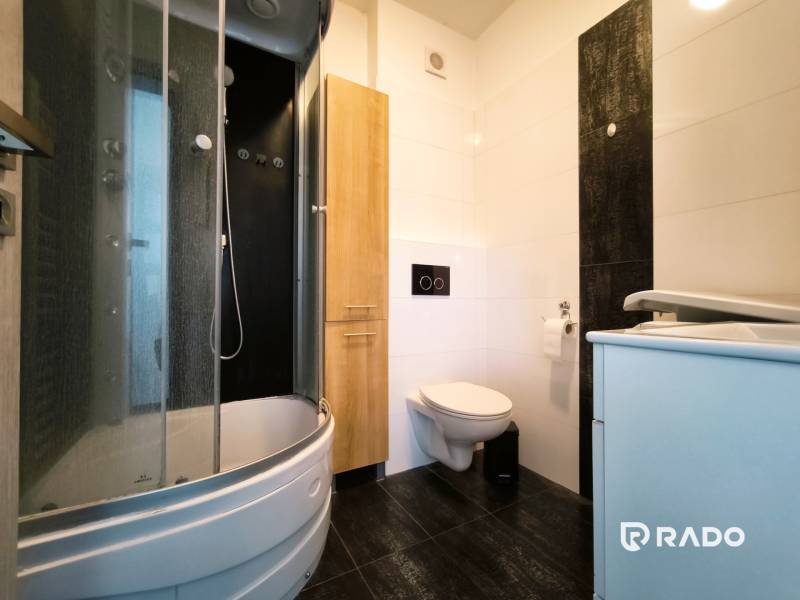 Bathroom with a shower, sink, and toilet in a 2-room apartment.