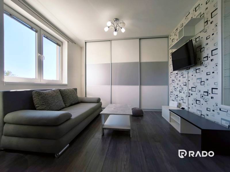 Living room in a two-room apartment with a sofa and a television on wall decoration.