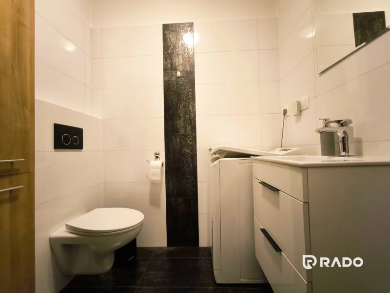 Bathroom in a 2-room apartment with a washing machine, sink, and toilet.