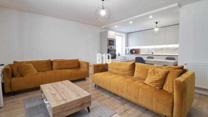 Living room in a family house with mustard sofas and a kitchenette.