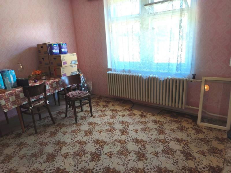A room in a family house with a carpet pattern and a table with chairs.