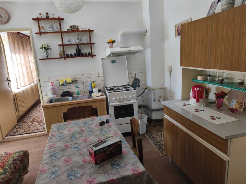 A kitchen in a family house with a dining table, a countertop, and decorations on the shelf.