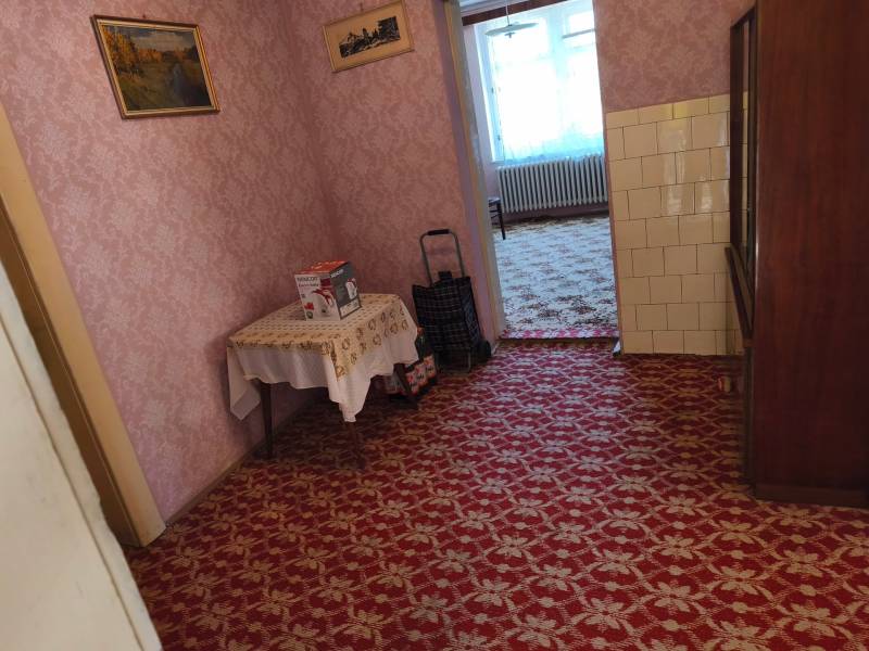 Interior of a family house with carpet, wallpaper, and furniture, including a painting on the wall.