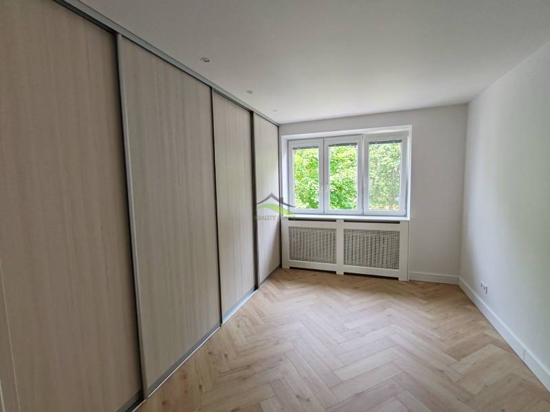 A room in a 2-room apartment with a built-in wardrobe and a window, light parquet flooring.
