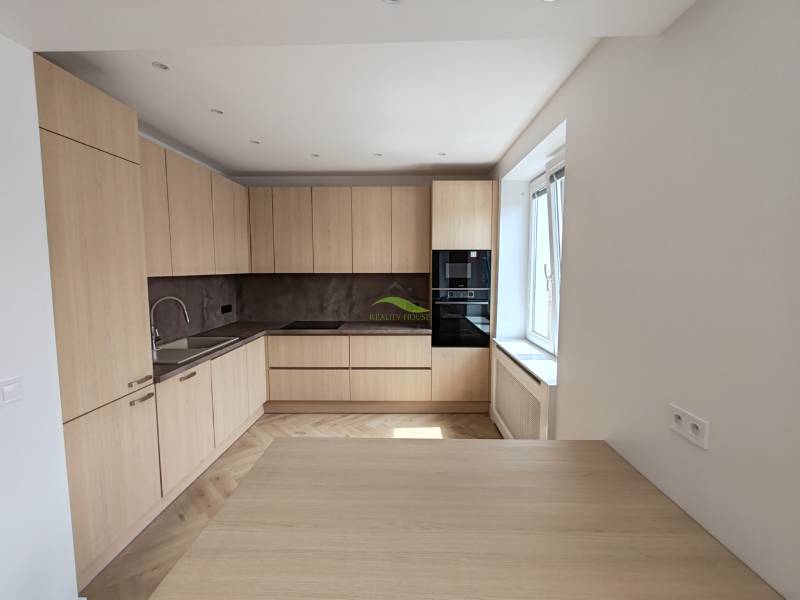 A kitchen in a 2-room apartment with wooden cabinets and built-in appliances.