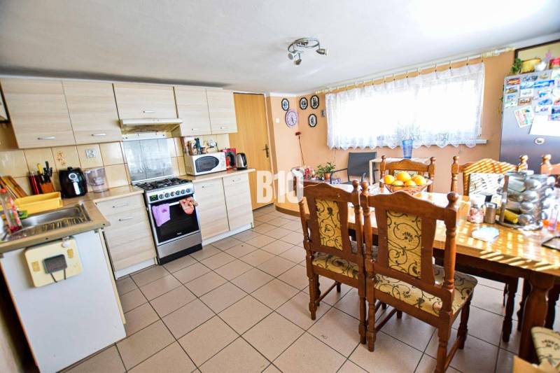 A kitchen in a family house with a large table, wooden chairs, and appliances.