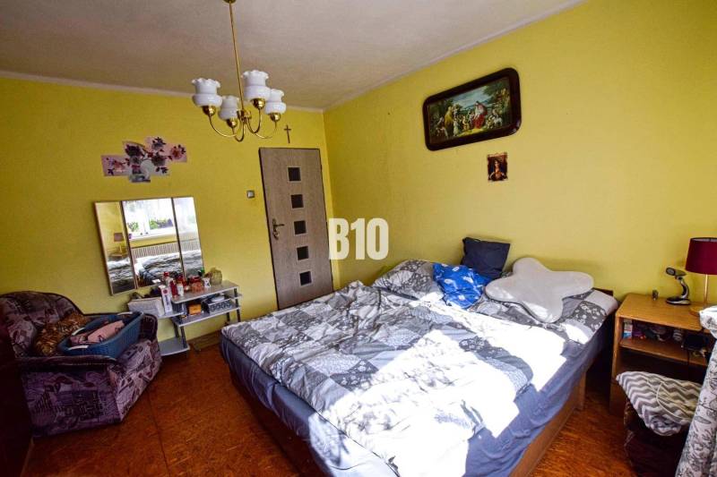 A bedroom in a family house with yellow walls, a bed, and wall decorations.