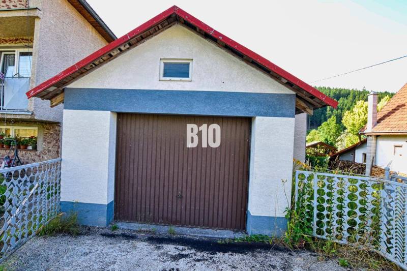 A garage at a family house in Turzovka, surrounded by greenery and a fence.