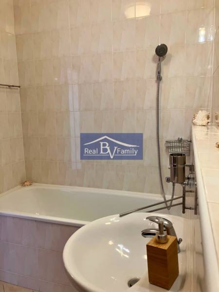 Bathroom with a bathtub, sink, and shower in a studio apartment.