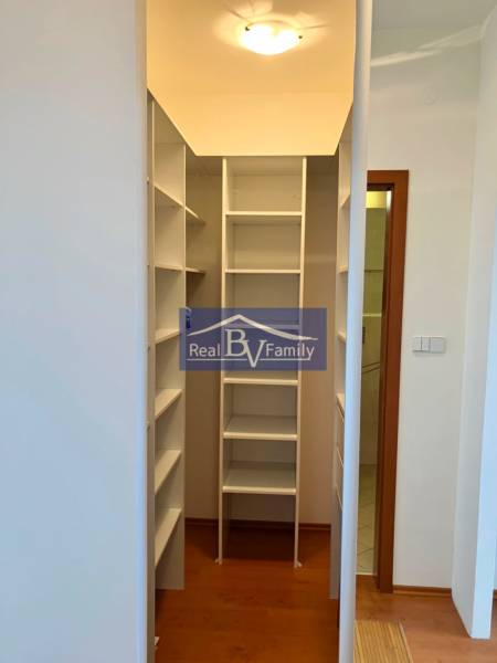 A wardrobe in a one-room apartment with white shelves and a wooden floor.