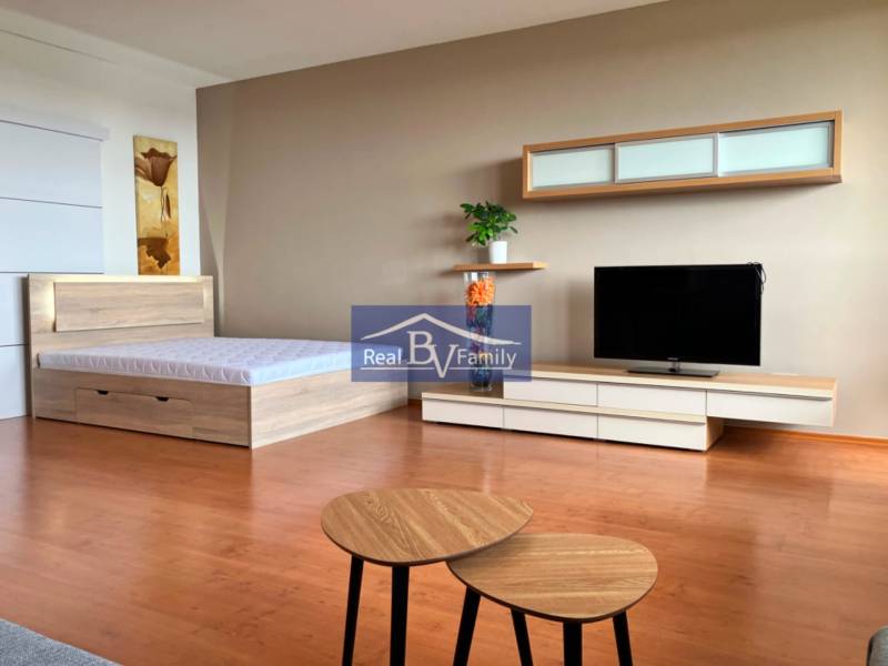 A studio apartment with a bed, TV, furniture, and wall decorations.