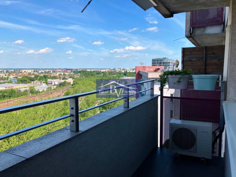View from the balcony of a 1-room apartment over the cityscape, railway, and greenery.