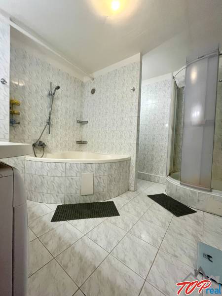 A bathroom with a corner bathtub and a shower in a 3-room apartment.