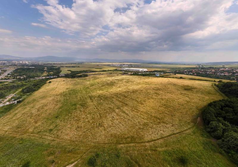 Extensive agricultural and forest lands in Košice, Luník IX district, under a cloudy sky.