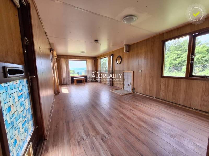 The interior of the cabin with wooden paneling, large windows, and a view of nature.