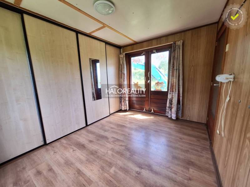 A room in a cabin with a wooden floor, large sliding doors, and built-in wardrobes.