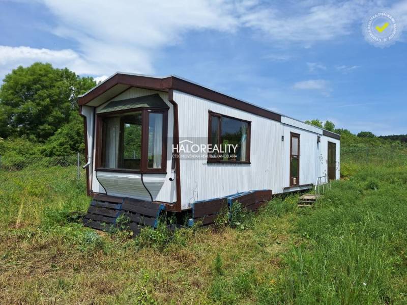 A mobile cottage in Boleráz surrounded by grass and trees in the background.