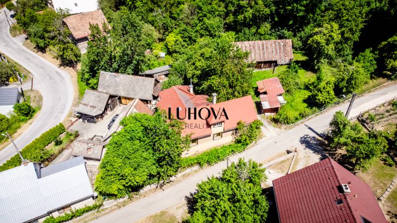 An aerial view of a family house in Púchov surrounded by greenery and nearby buildings.