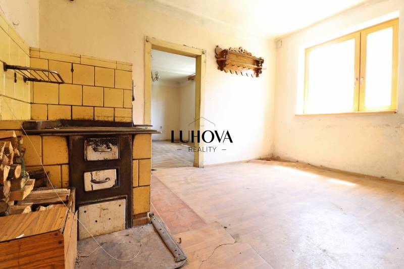 A kitchen in a family house with a tiled stove and wooden floor.