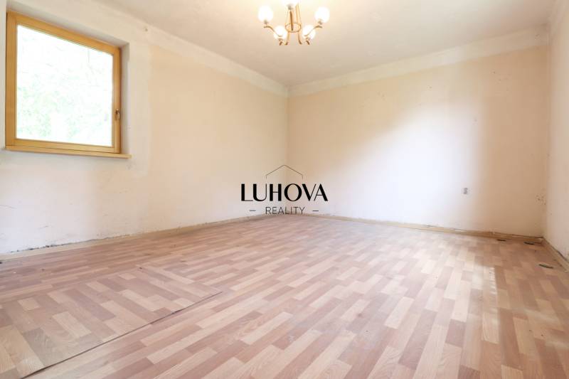 An empty room with a wooden floor and a window in a family house, neutral walls.