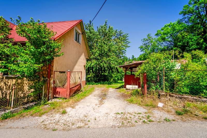 A family house on a street in Púchov, surrounded by greenery and an access road.