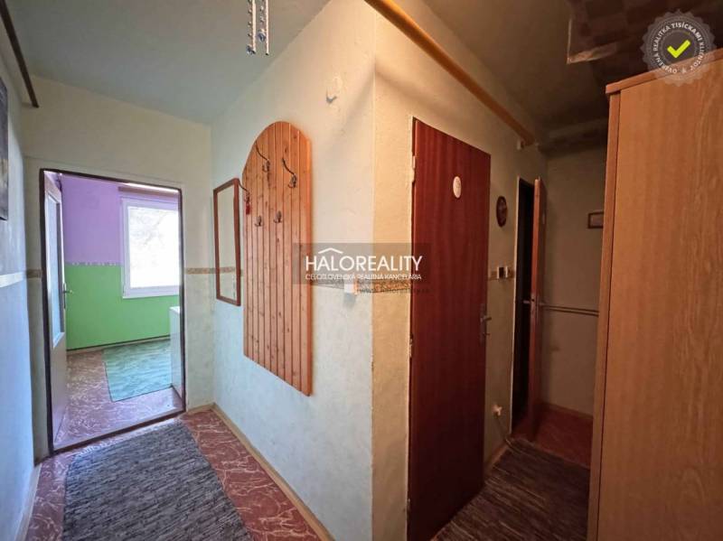 A hallway in a one-room apartment with built-in wardrobes and a colorful room in the background.