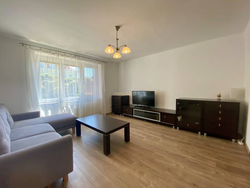 Living room in a two-room apartment with a sofa, table, and television, minimalist furnishings.