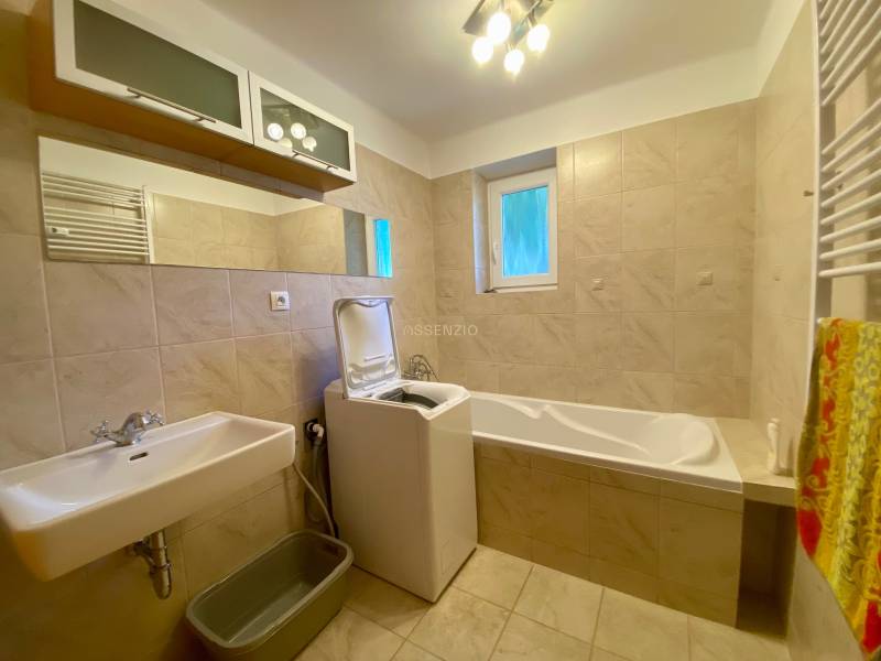 A bathroom in a 2-room apartment with a bathtub, sink, and washing machine.