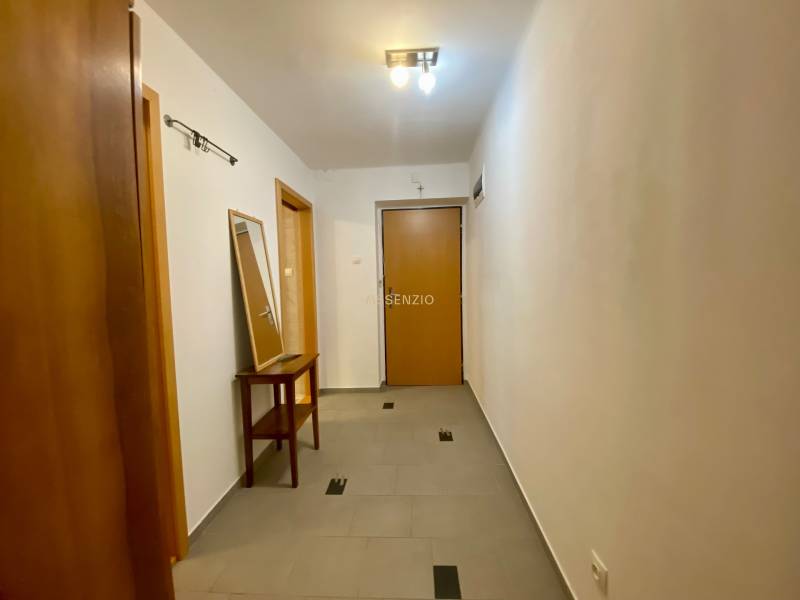 A hallway in a 2-room apartment with wooden doors and a mirror on the table.