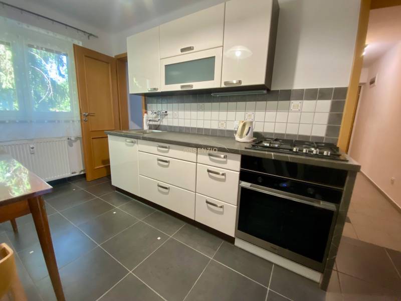 Kitchen in a 2-room apartment with white cabinets and black appliances.