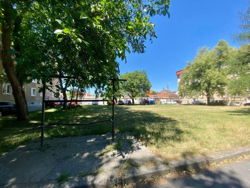 Peaceful Studentská Street in Trnava with apartment buildings and a green park in the background.