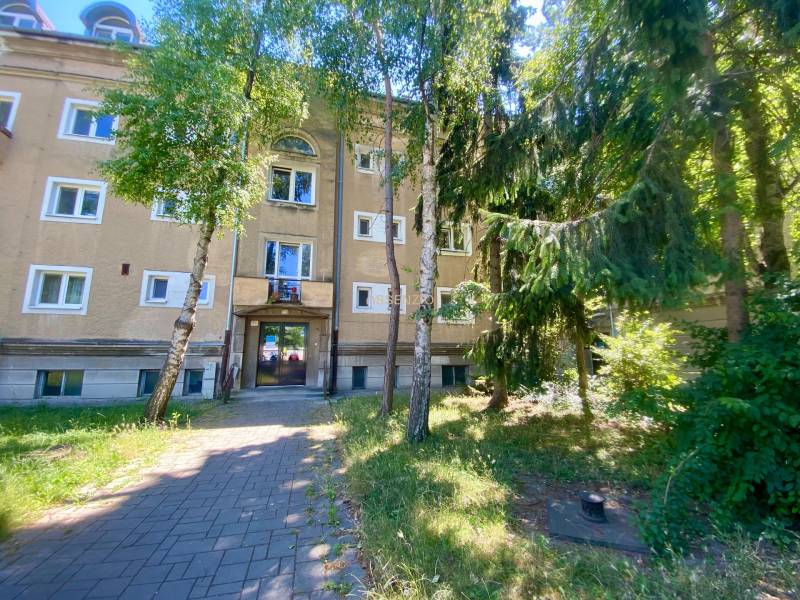 An apartment building on Študentská Street in Trnava surrounded by trees and a green garden.