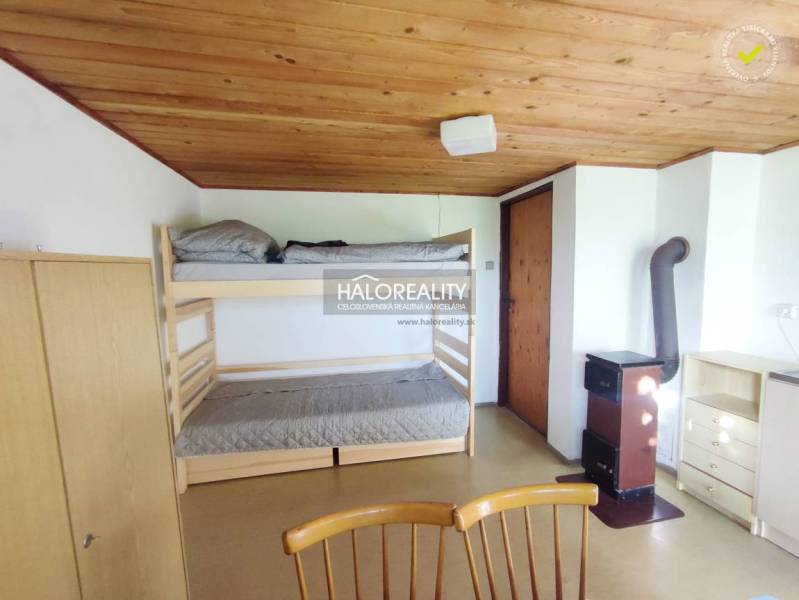 An interior with a bunk bed, wooden ceiling, wardrobe, and stove in Záhrady.