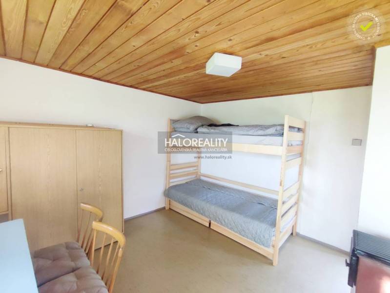 A simple room with a wooden panel ceiling, a bunk bed, and a wardrobe in the garden.