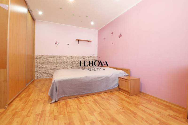A bedroom in a 3-room apartment with wooden flooring, pink walls, and furniture.
