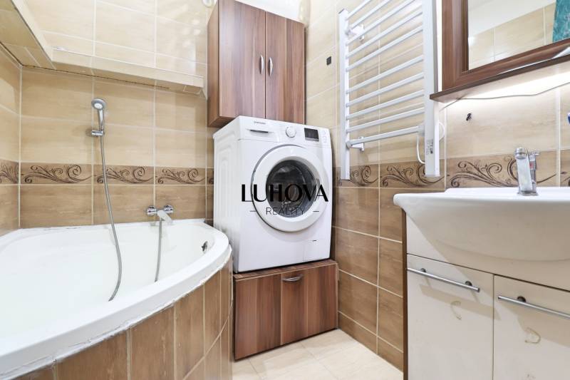 Bathroom with a bathtub, washing machine, and cabinets in a 3-room apartment.